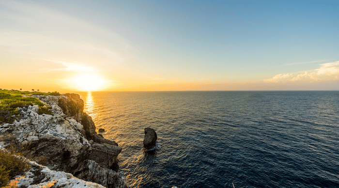 Sun setting over the ocean and cliff